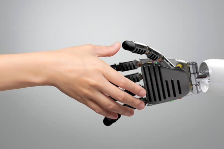 KI-Korrektur_724x483 Eine menschliche Hand schüttelt die Hand eines Roboters – Symbol für die Zusammenarbeit zwischen Mensch und Künstlicher Intelligenz bei der KI-Text Korrektur.
