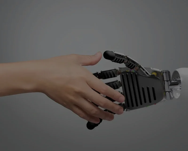 Eine menschliche Hand reicht einer robotischen Hand die Hand zum Handschlag – Symbol für professionelle KI-Text-Korrektur und menschliche Optimierung.